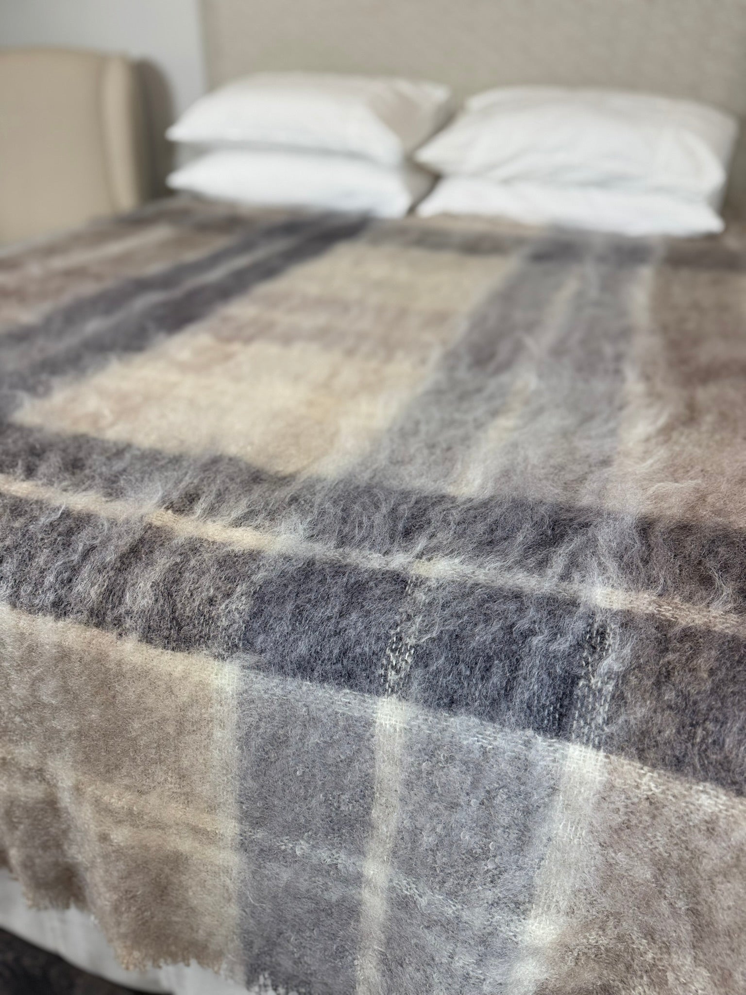 Plaid blanket on a bed with pillows in a bedroom setting